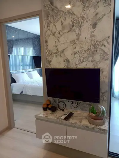 Modern bedroom with marble accent wall and mounted TV, showcasing luxury interior design.