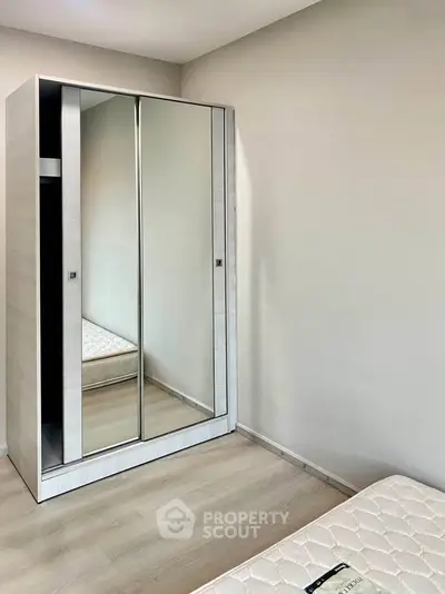Minimalist bedroom with mirrored wardrobe and simple mattress, perfect for modern living.