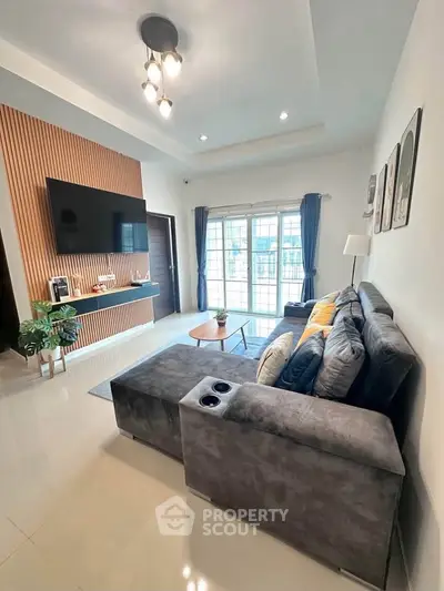 Spacious modern living room with large sofa and wall-mounted TV, perfect for relaxation.