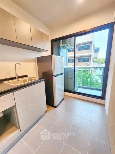 Modern kitchen with sleek cabinetry and balcony view in urban apartment