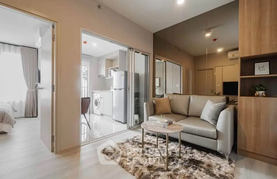 Modern apartment interior with cozy living room and sleek kitchen featuring washing machine and fridge.