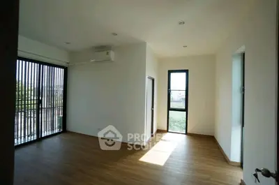 Spacious empty room with large windows and wooden flooring, perfect for customization.
