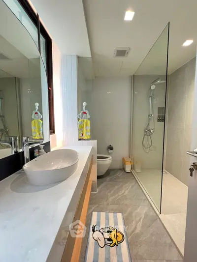 Modern bathroom with glass shower and stylish vanity in luxury apartment.