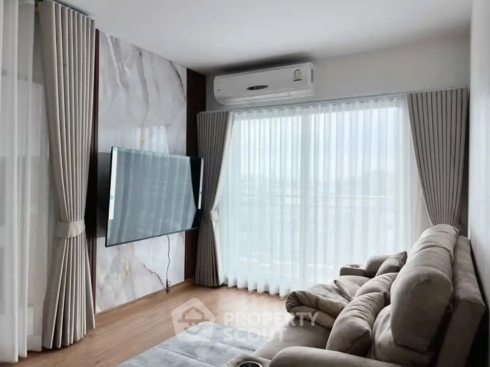Modern living room with large TV, plush sofa, and floor-to-ceiling windows with elegant curtains.