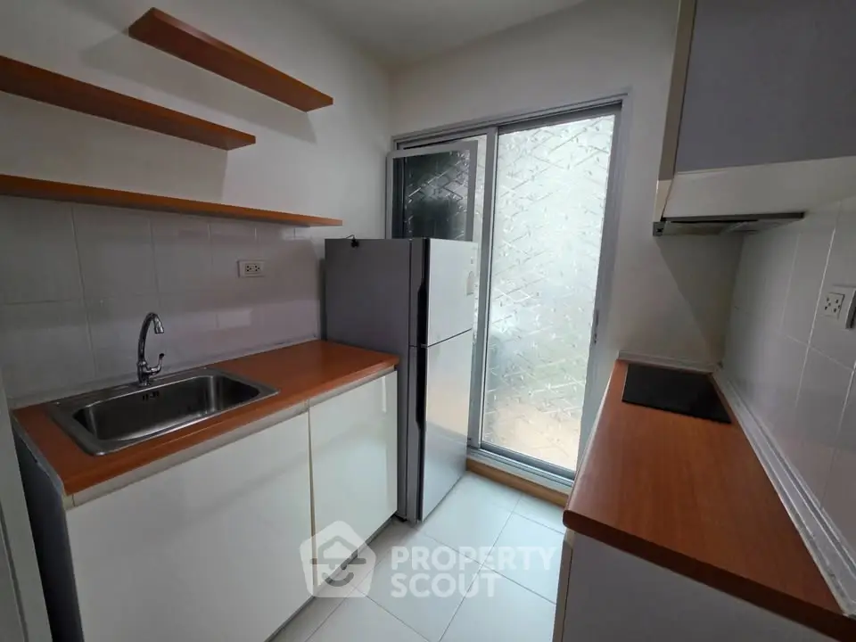 Modern kitchen with sleek countertops and ample storage space, featuring a large fridge and electric stove.