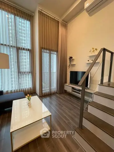 Modern living room with high ceilings, large windows, and stylish staircase in a contemporary apartment.