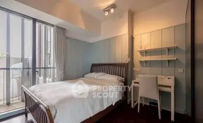 Cozy bedroom with balcony access and study area, featuring elegant wooden furniture.