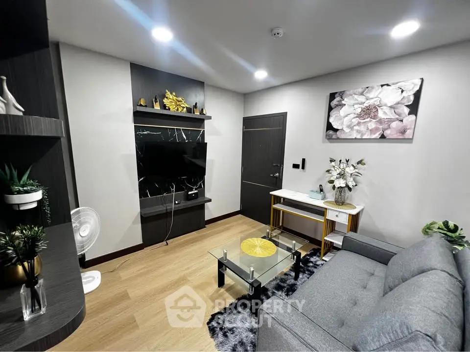 Modern living room with stylish decor, featuring a sleek TV setup, elegant furniture, and contemporary artwork.