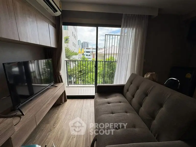 Modern living room with balcony view, featuring sleek furniture and natural light.