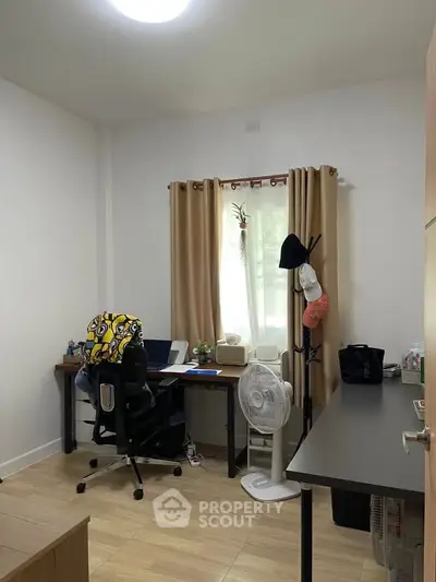 Cozy study room with desk, chair, and natural light through window.