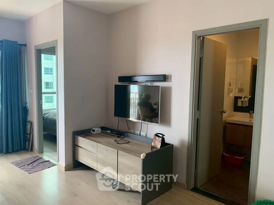 Modern living room with wall-mounted TV and adjacent bathroom in stylish apartment.