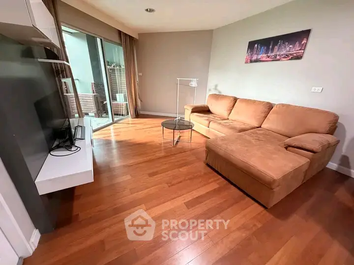 Spacious living room with modern decor and large windows opening to a balcony.