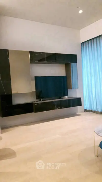 Modern living room with sleek black entertainment unit and large TV, featuring elegant floor-to-ceiling curtains.