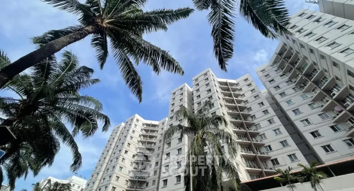 Stunning high-rise apartment building with palm trees and clear blue sky