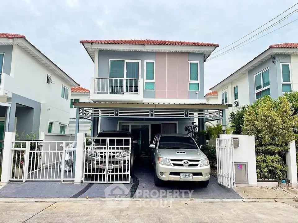 Modern two-story house with carport and gated driveway in a suburban neighborhood.