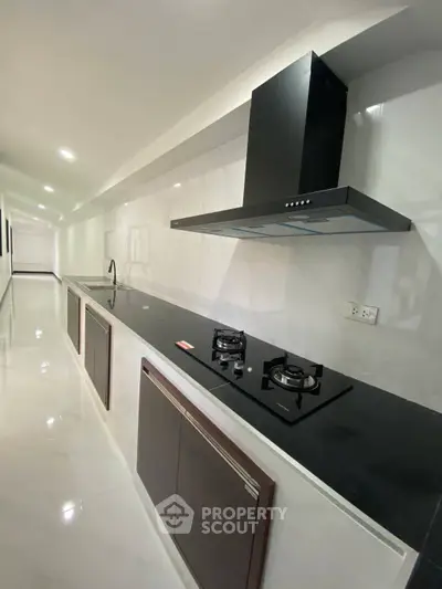 Sleek modern kitchen with black countertop and gas stove in a spacious layout