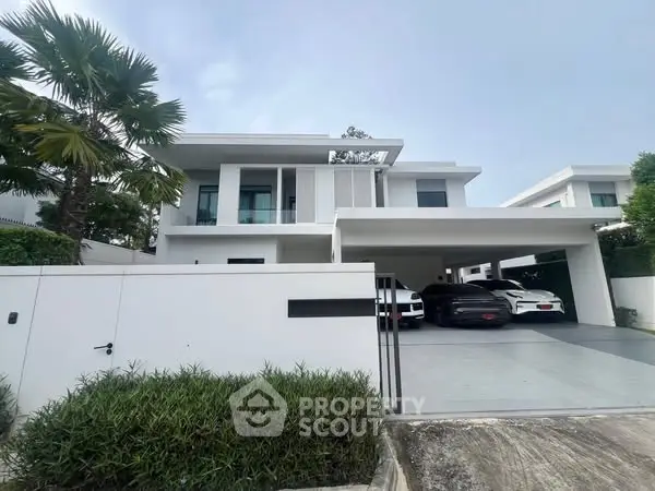 Luxurious modern white villa with spacious driveway and lush greenery