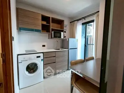 Modern compact kitchen with washing machine and dining area in a cozy apartment.