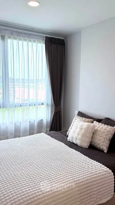 Cozy bedroom with large window and elegant curtains, featuring a plush bed and stylish decor.