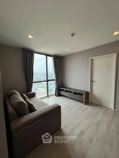 Spacious living room with large window offering city views, modern decor, and cozy seating area.
