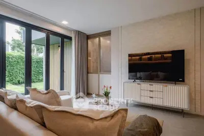 Elegant living room with modern decor and large windows overlooking lush greenery.