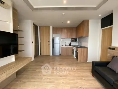 Modern open-layout living room with sleek kitchen, wooden flooring, and built-in TV unit.