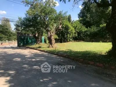 Spacious green garden with mature trees and gated entrance