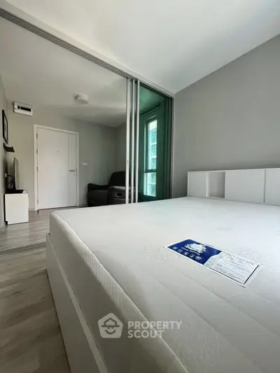 Spacious modern bedroom with large bed and sliding glass doors leading to a cozy living area.