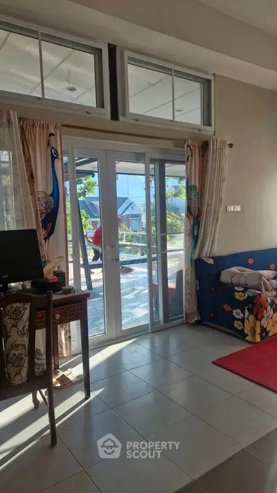 Spacious living room with large windows and elegant peacock curtains, offering a serene garden view.