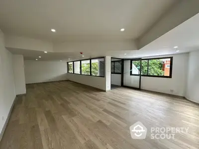 Spacious and modern living room with abundant natural light, sleek hardwood floors, and a contemporary open floor plan, ideal for entertaining and comfortable living.