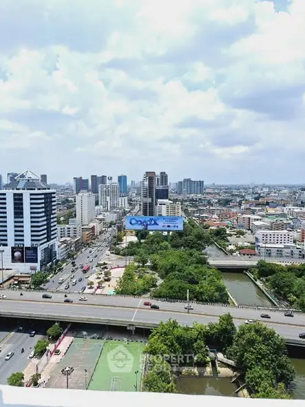 Stunning cityscape view from a high-rise building showcasing urban skyline and lush greenery.