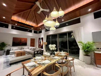 Luxurious open living and dining area with elegant decor and high wooden ceiling.