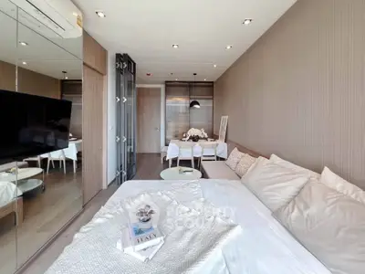 Modern bedroom with elegant decor and cozy ambiance, featuring a stylish bed and mirrored wall.