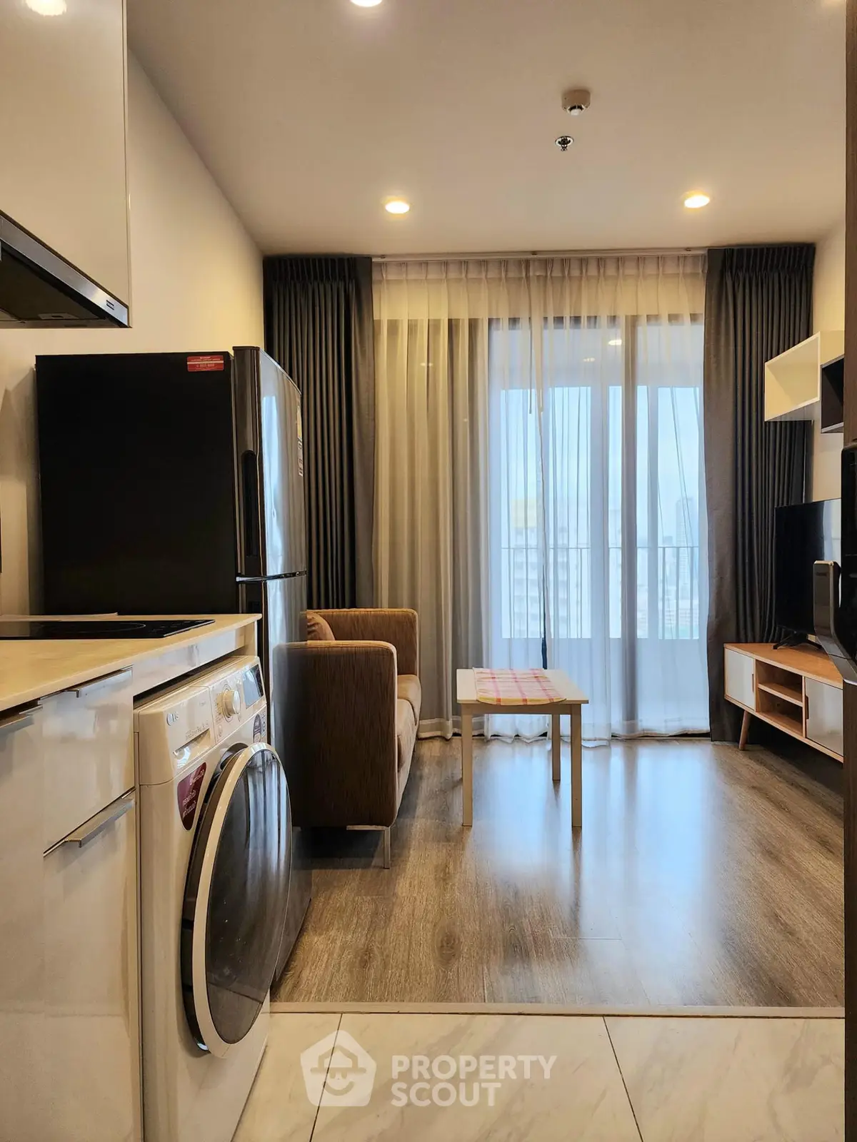 Modern living room with open kitchen, featuring a washing machine and cozy seating area.