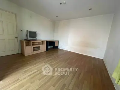 Spacious living room with wooden flooring and TV stand, ideal for cozy gatherings.