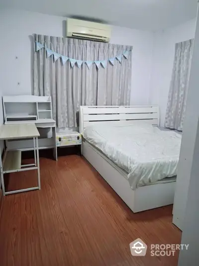 Cozy bedroom with wooden flooring and modern white furniture, ideal for comfort and relaxation.