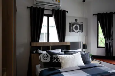 Cozy bedroom with modern decor, featuring a stylish bed, dark curtains, and a unique camera-themed wall art.
