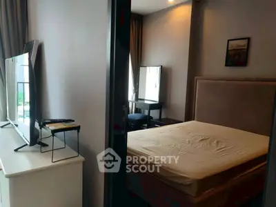 Modern bedroom with large TV and natural light, ideal for cozy living.