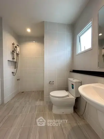 Modern bathroom with sleek tiles and shower area in a contemporary home.