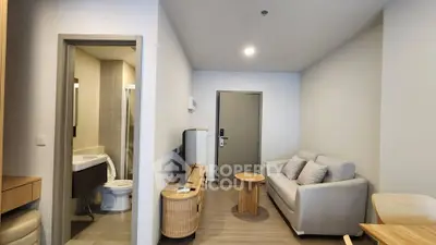 Modern living room with cozy sofa, TV, and bathroom access in a stylish apartment.