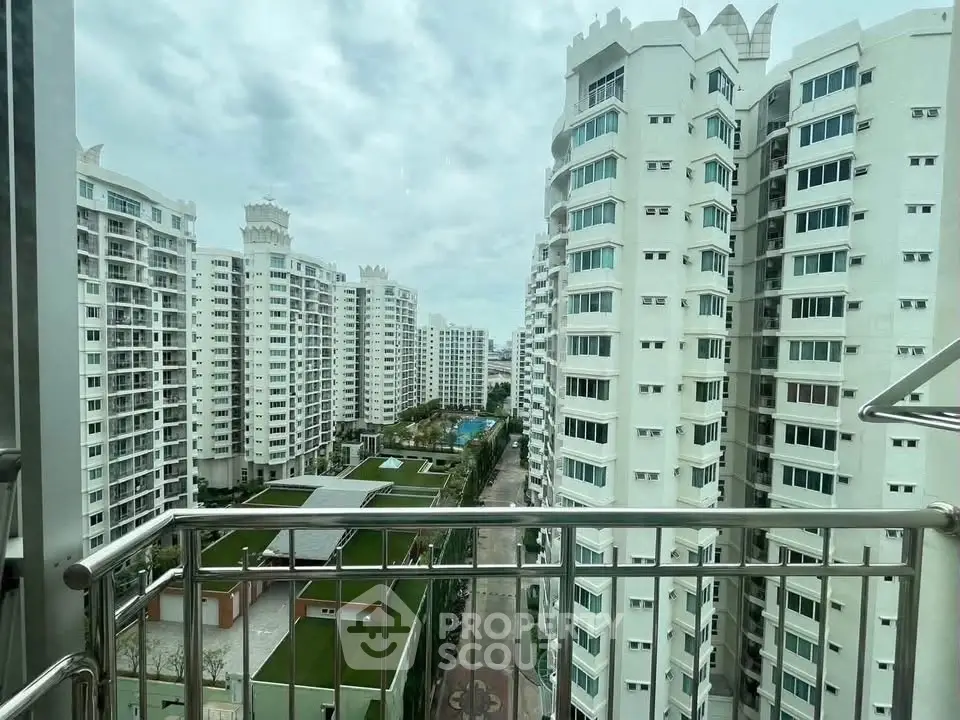 Stunning view from balcony overlooking modern high-rise residential buildings and lush green spaces.