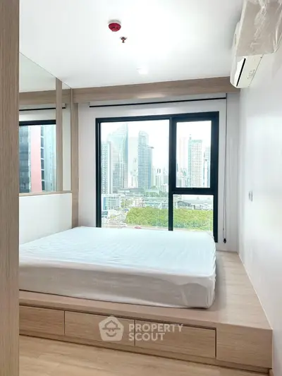 Modern bedroom with city view, featuring a platform bed and large windows in a high-rise apartment.