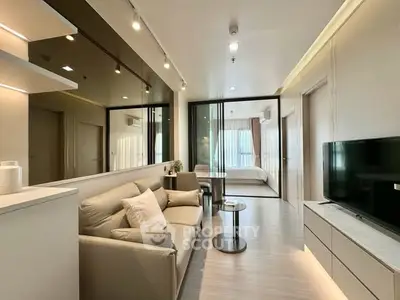 Modern living room with sleek design and open layout leading to a cozy bedroom.