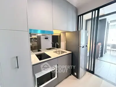 Modern compact kitchen with sleek cabinetry and built-in appliances in a stylish apartment.