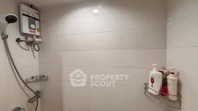 Modern bathroom with shower and water heater, featuring sleek white tiles and convenient storage shelves.