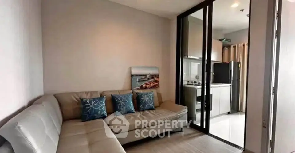 Modern living room with sleek kitchen, featuring a cozy sectional sofa and stylish decor.