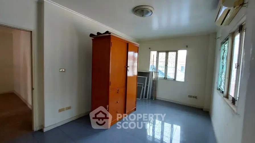 Spacious room with natural light and wooden wardrobe, ideal for versatile use.