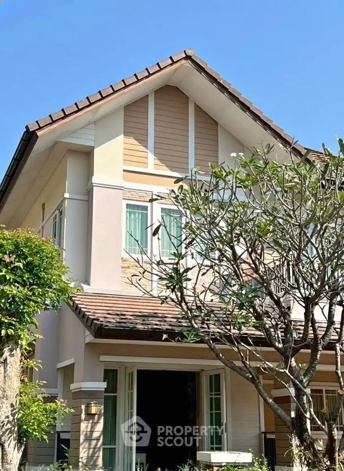 Charming two-story house with a gabled roof and lush garden, perfect for family living.