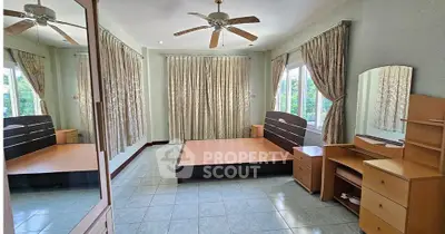 Spacious bedroom with large windows and elegant curtains, featuring a wooden bed frame and matching furniture.