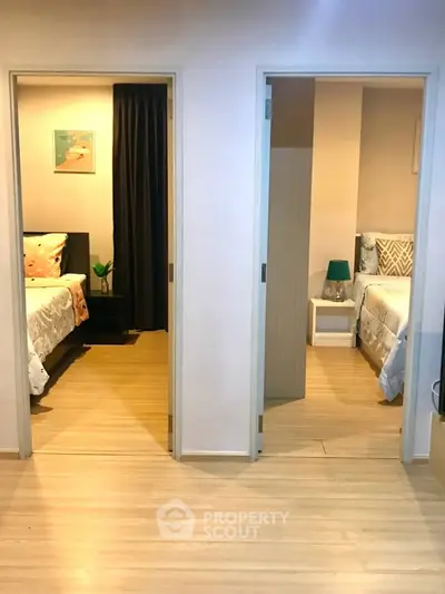 Modern dual-bedroom layout with wooden flooring and stylish decor, perfect for comfortable living.